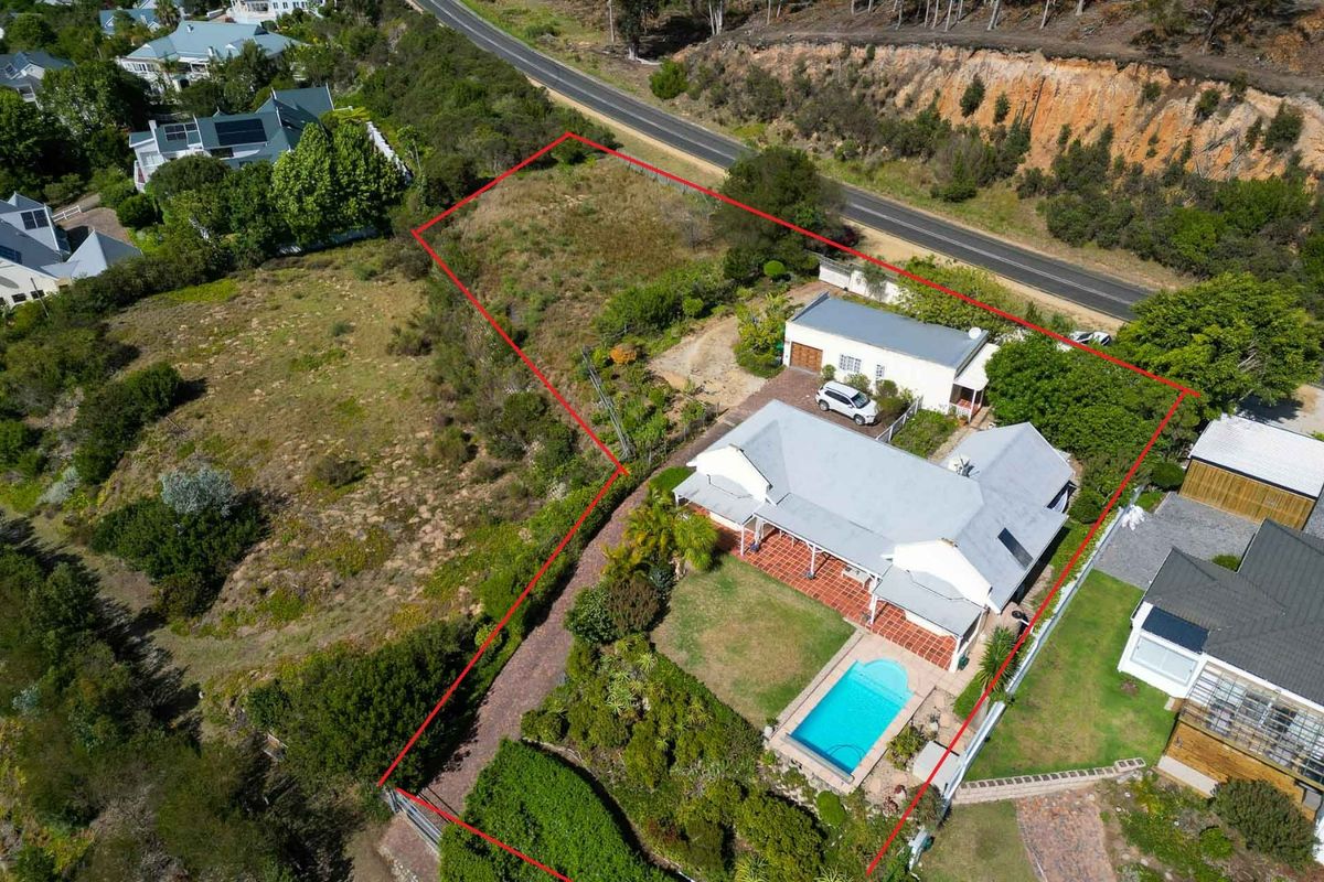 Aerial view of a residential property featuring a main house with a tiled patio, a swimming pool, and a detached garage on a large plot.