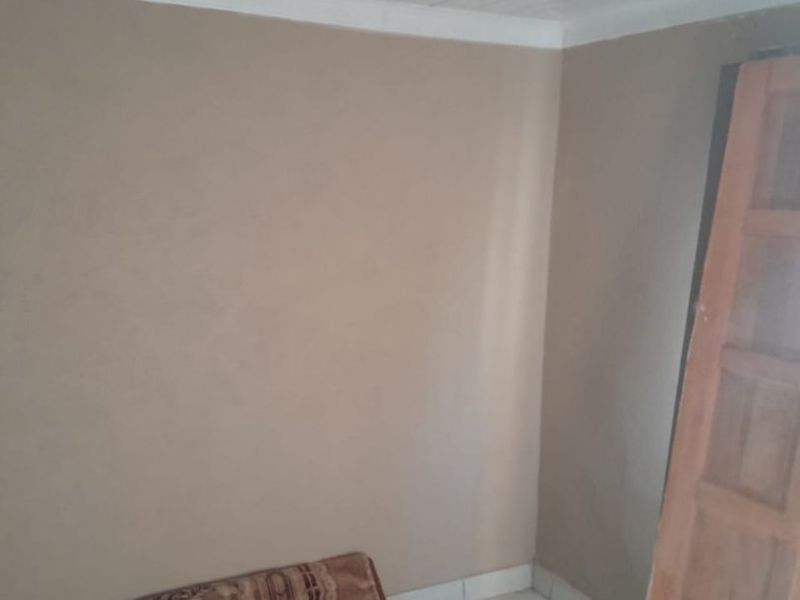 An empty bedroom featuring tiled flooring, a tongue and groove ceiling with coving, and an uninstalled wooden door.