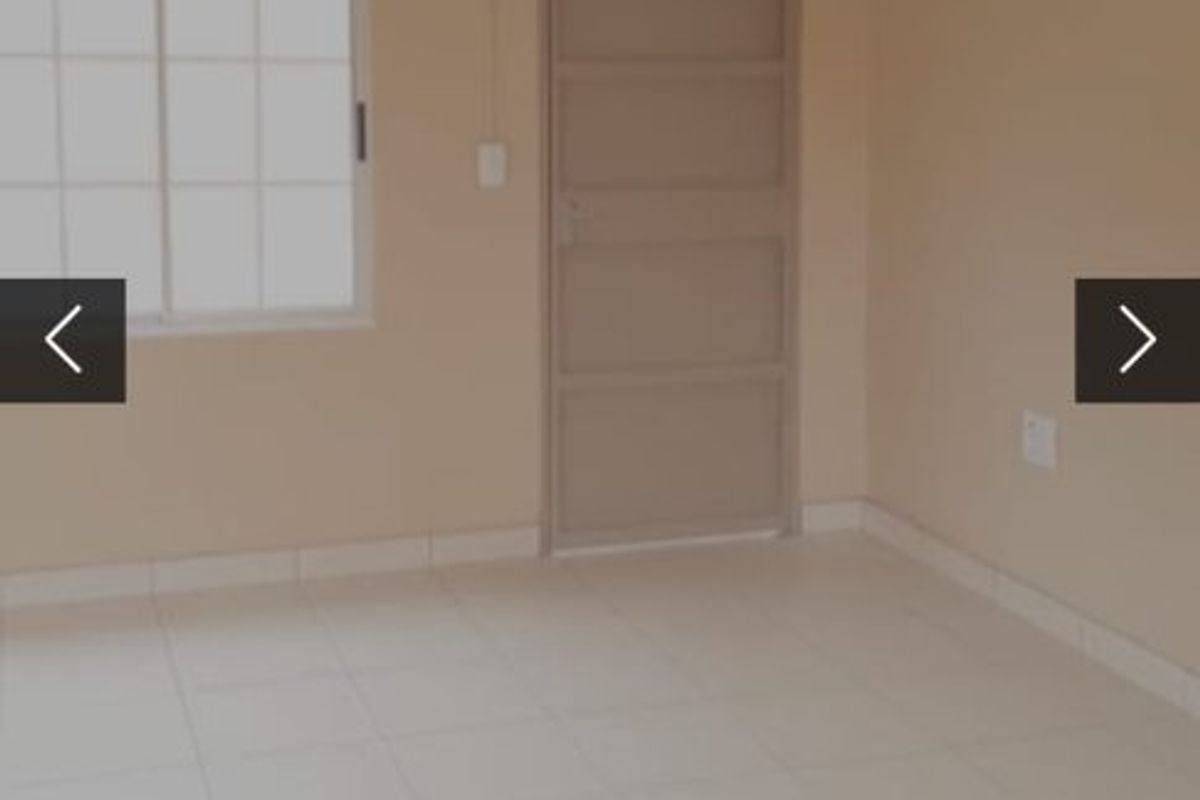 A clean, empty bedroom featuring neutral wall paint, tiled flooring, and a simple sliding window.
