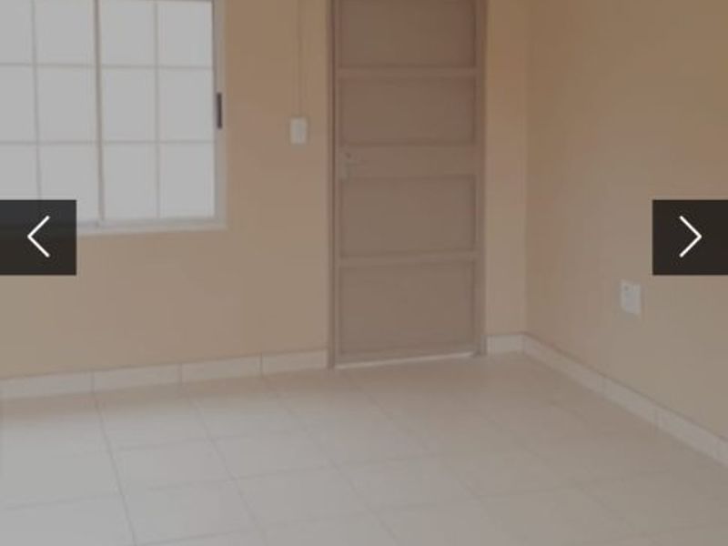 A clean, empty bedroom featuring neutral wall paint, tiled flooring, and a simple sliding window.