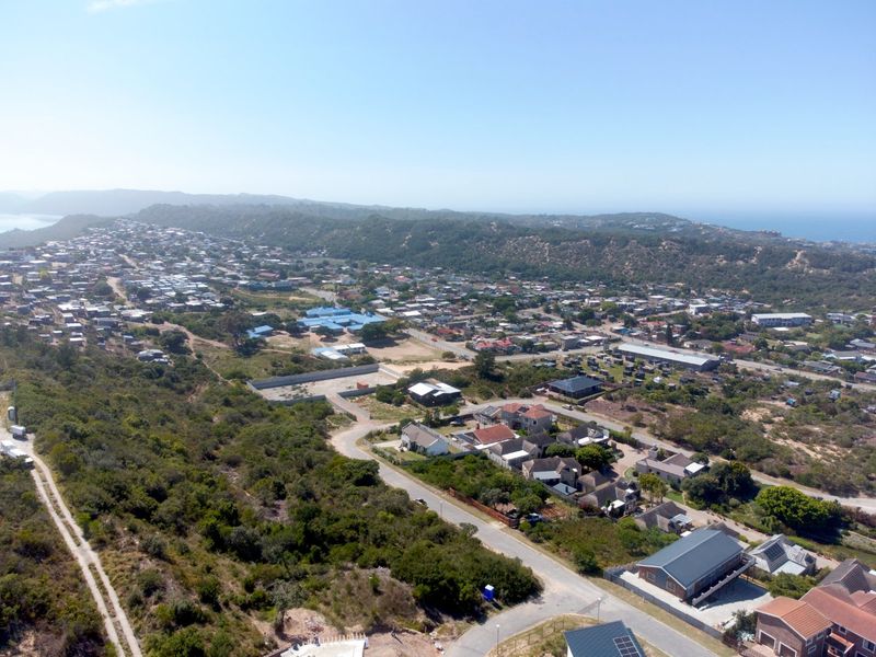 An aerial view of a residential coastal neighborhood, showcasing the surrounding landscape, local infrastructure, and proximity to the coastline.