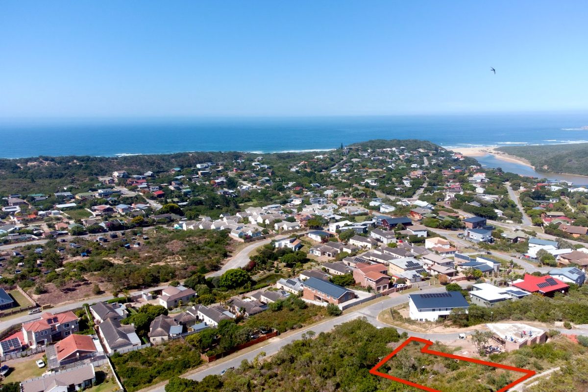 Aerial view of a vacant residential plot highlighted in red, situated within a coastal neighborhood with ocean views.