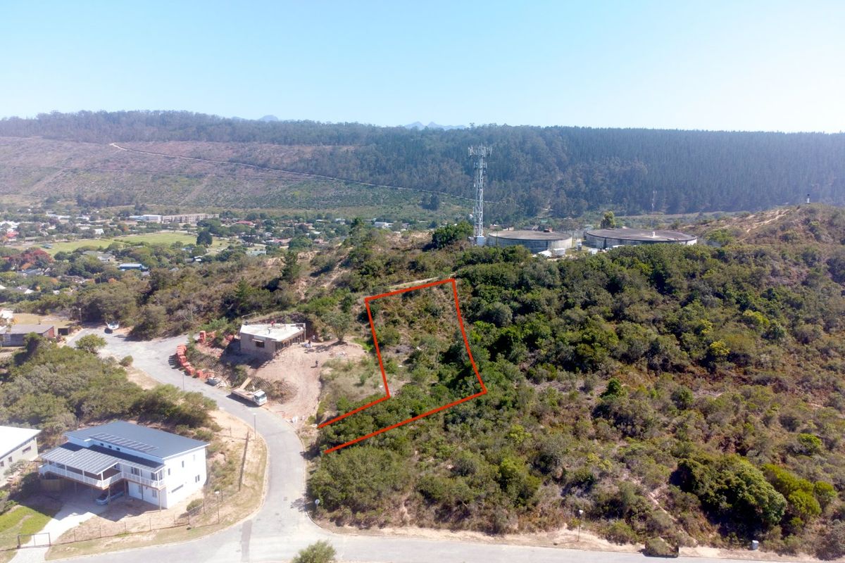 Aerial view of a sloped, undeveloped residential plot featuring native vegetation and surrounding hillside landscape.