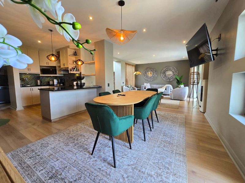 Spacious open-plan living and dining area featuring modern kitchen cabinetry, stone countertops, recessed lighting, and high-quality hardwood flooring throughout.