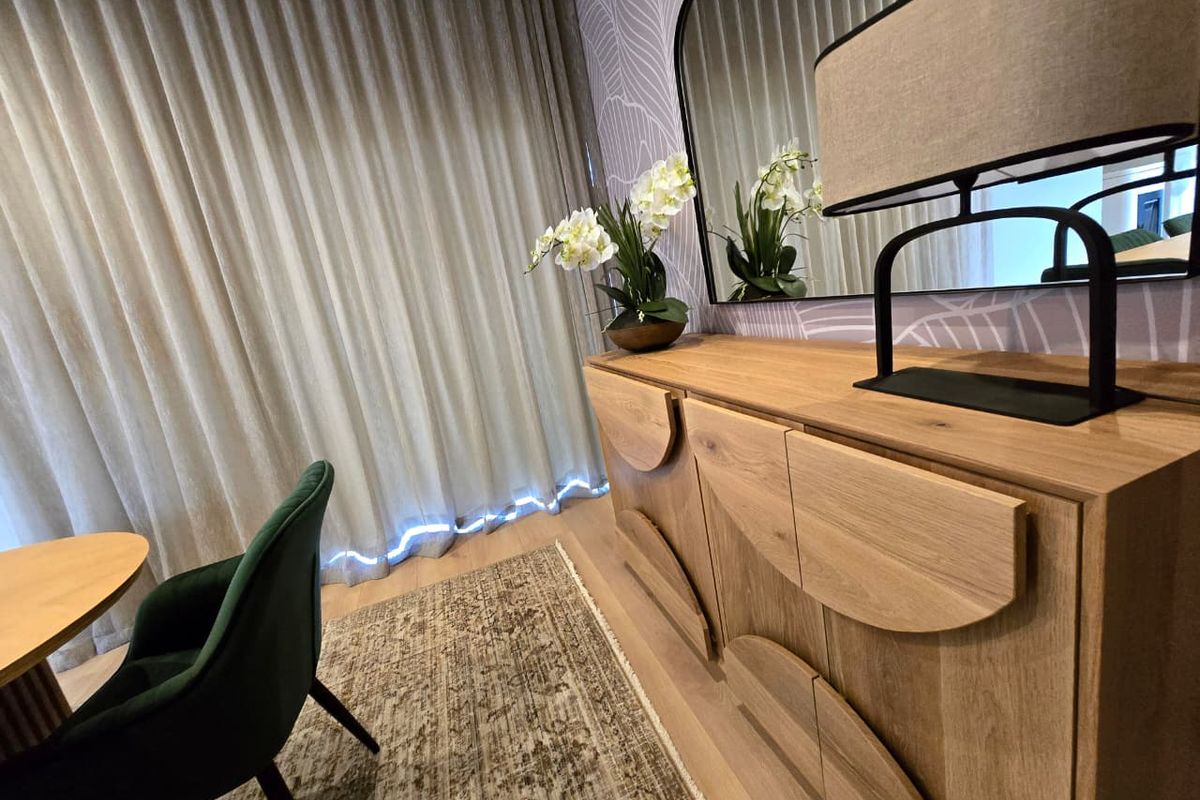 A well-appointed living area featuring modern wallpaper, neutral floor-to-ceiling curtains, and high-quality laminate flooring.