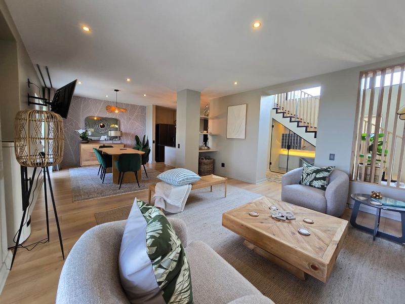 Spacious open-plan living and dining area featuring modern timber flooring, recessed lighting, and a contemporary staircase with a timber slat feature wall.