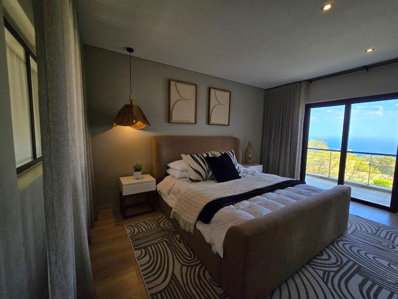 A well-appointed bedroom featuring modern recessed lighting, laminate flooring, and a large sliding glass door providing access to a balcony with scenic views.