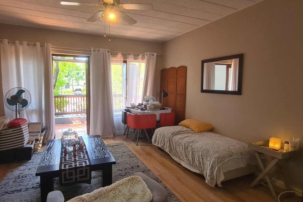 A living room featuring laminate flooring, a ceiling fan, and sliding glass doors providing access to an outdoor balcony area.