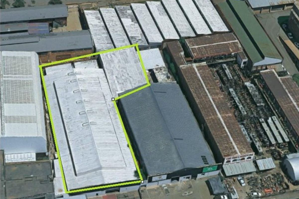 Aerial view of an industrial warehouse facility highlighting the roof structure and surrounding commercial property layout.
