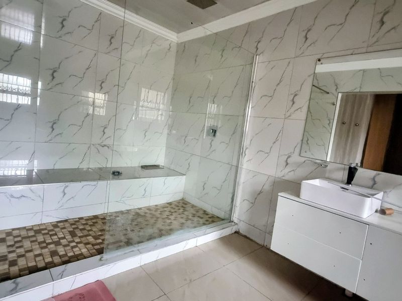 Modern bathroom featuring a spacious walk-in shower with a built-in bench, glass enclosure, and a sleek wall-mounted vanity with a vessel sink.