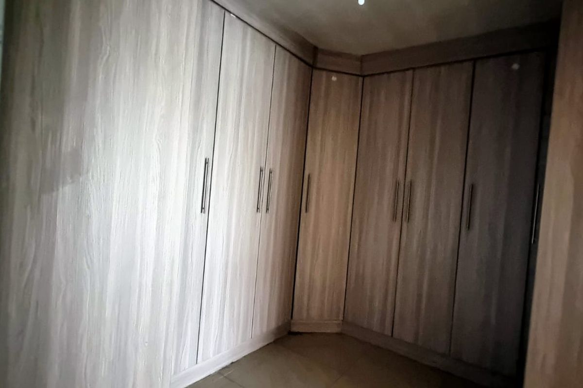 A bedroom featuring extensive floor-to-ceiling built-in wooden cupboards providing ample storage space.