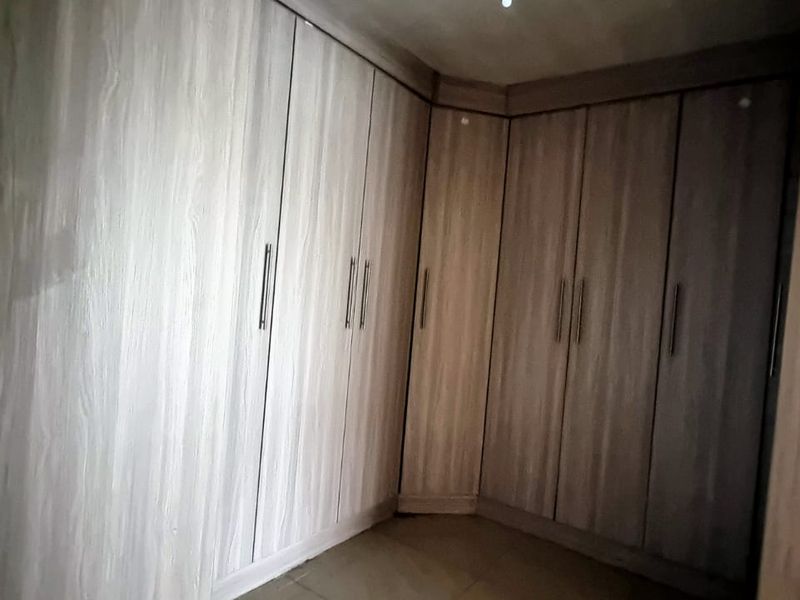 A bedroom featuring extensive floor-to-ceiling built-in wooden cupboards providing ample storage space.