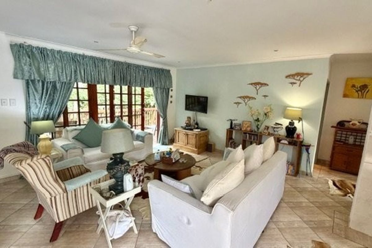 Spacious living room featuring tiled flooring, a ceiling fan, and large sliding glass doors providing access to the outdoor area.