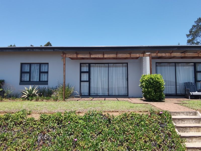 Rear exterior view of the townhouse featuring a timber pergola, sliding glass doors, and a landscaped garden with concrete stairs.