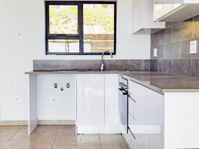 Modern kitchen featuring white cabinetry, tiled backsplash, built-in oven, and hob, with an open space ready for appliance installation.