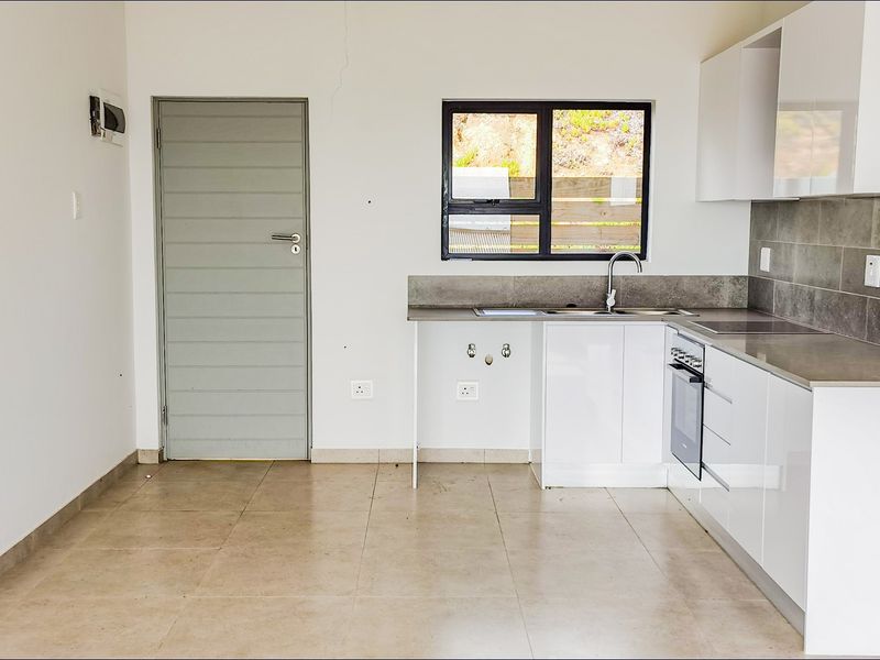 Modern kitchen featuring white cabinetry, tiled splashbacks, built-in oven, and tiled flooring, offering a clean and functional space.