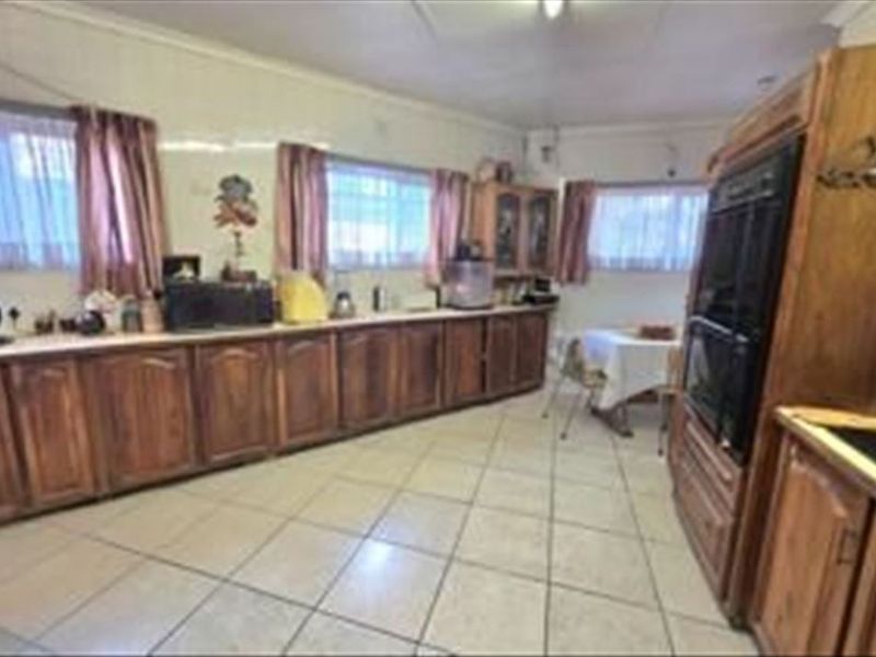 A spacious kitchen featuring traditional wooden cabinetry, tiled flooring, and a built-in oven, offering a functional layout with ample storage space.