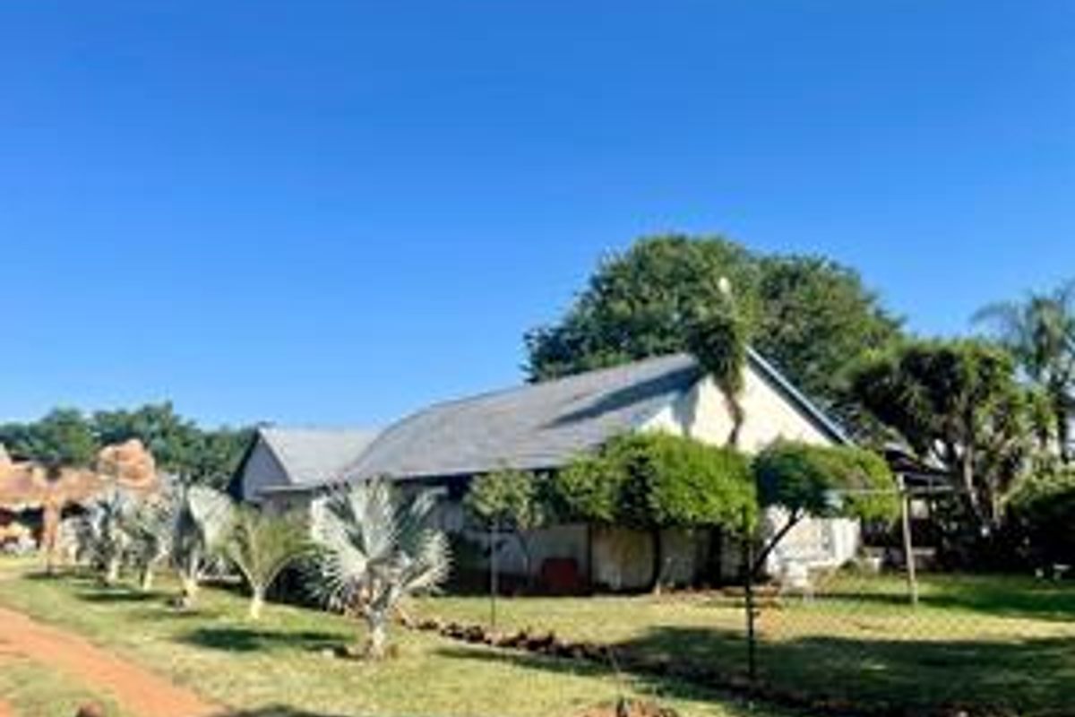 A view of the rear exterior of the farm property, featuring a pitched metal roof and surrounding garden area.