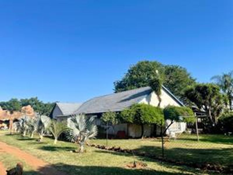 A view of the rear exterior of the farm property, featuring a pitched metal roof and surrounding garden area.