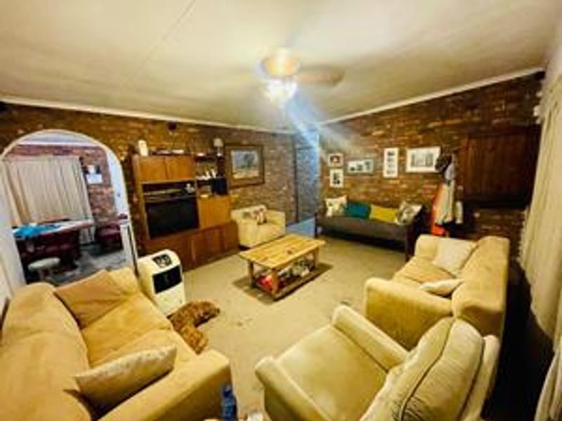 A spacious living room featuring exposed brick walls and a ceiling fan, offering a rustic aesthetic with potential for modern updates.