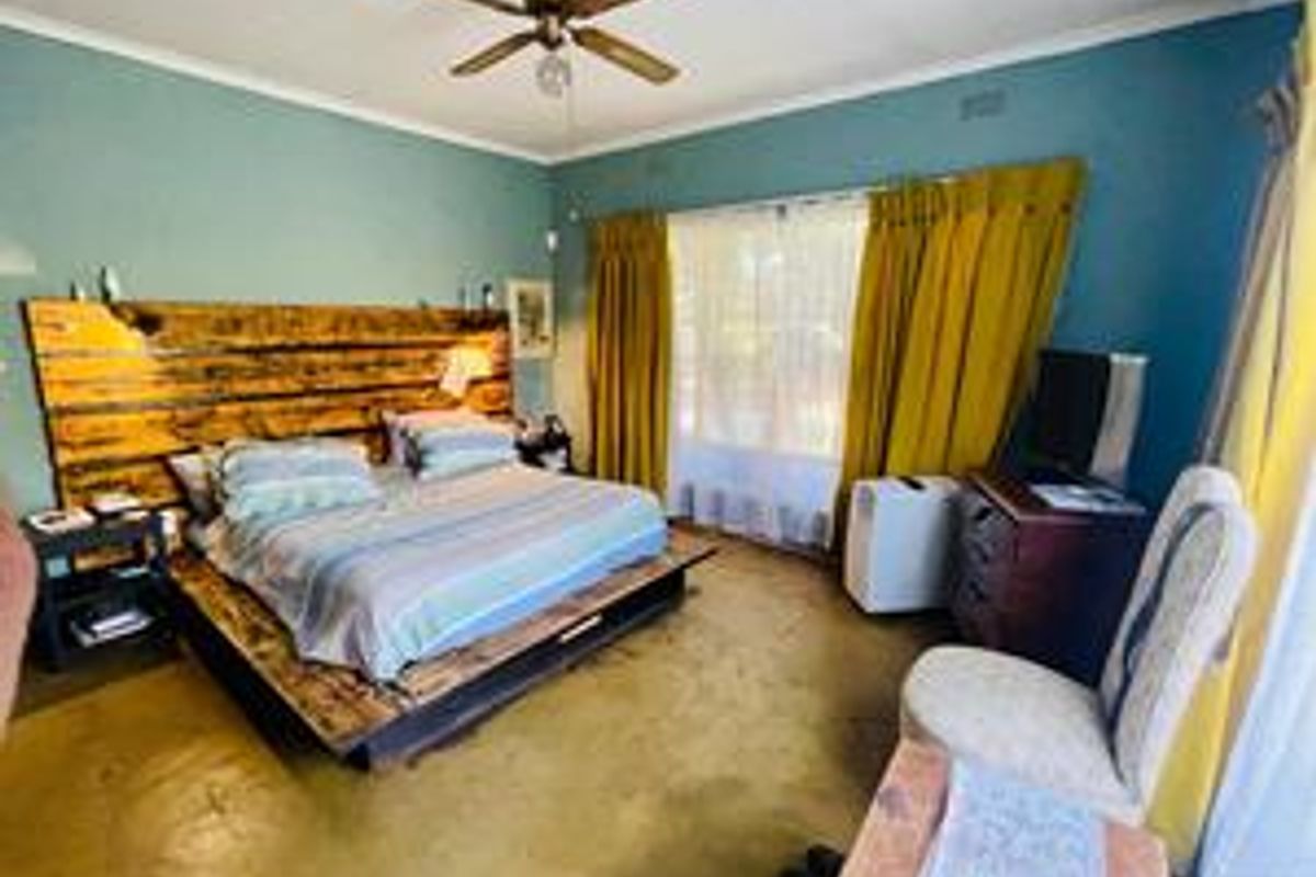 A spacious bedroom featuring a polished concrete floor, ceiling fan, and large windows with natural light.