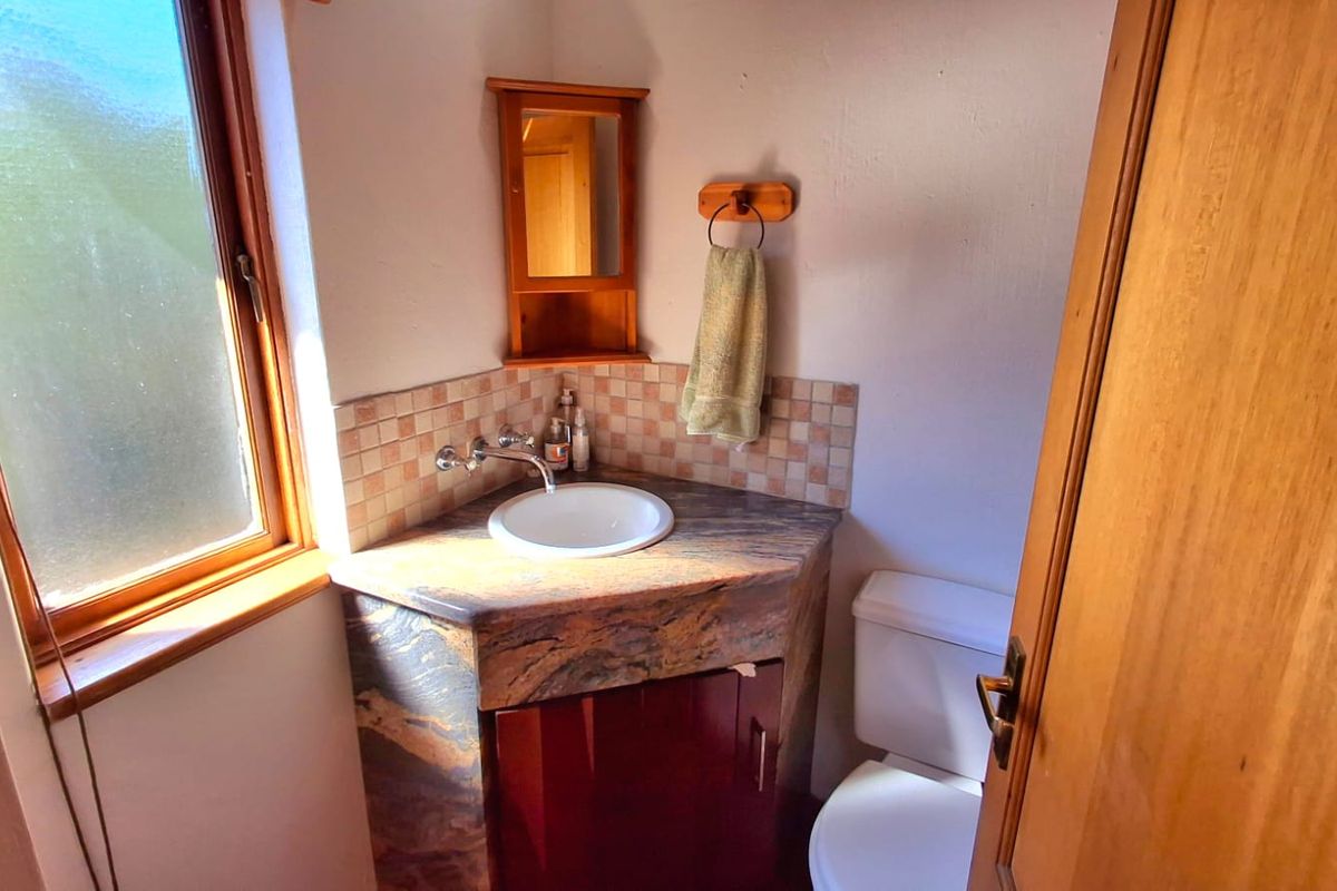 Compact bathroom featuring a corner vanity with stone countertop, drop-in basin, wall-mounted tap, and a matching corner medicine cabinet.