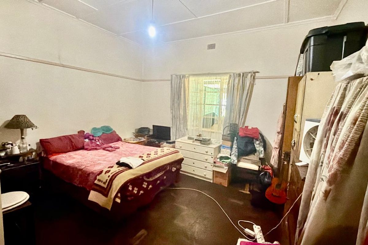 A bedroom featuring traditional picture rails and a ceiling rose, requiring cosmetic updates to the flooring and wall finishes.