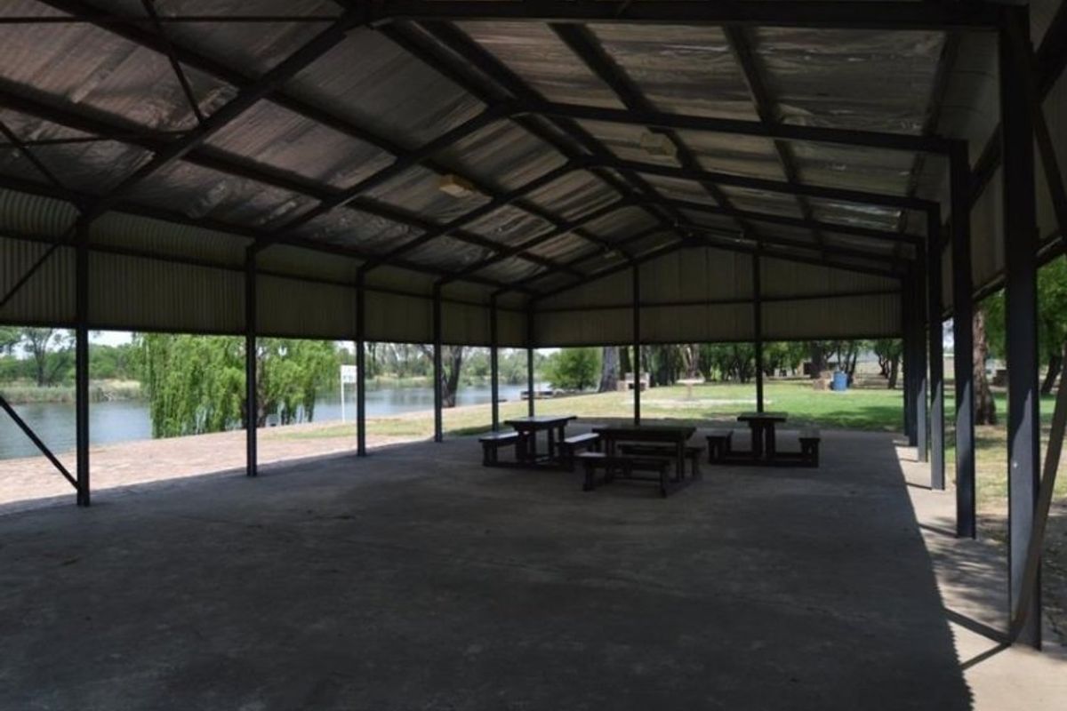 A large, open-air covered pavilion featuring a durable steel frame and metal roof, overlooking a scenic waterfront area.