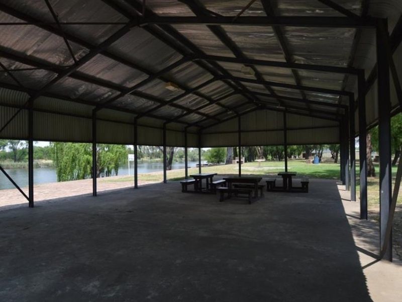 A large, open-air covered pavilion featuring a durable steel frame and metal roof, overlooking a scenic waterfront area.
