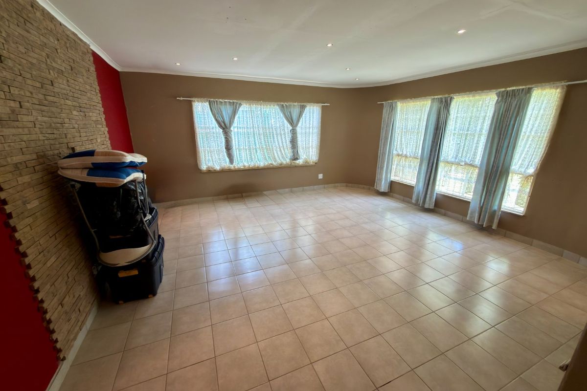 Spacious living room featuring tiled flooring, recessed downlights, and a textured stone feature wall, offering a versatile blank canvas for interior design.