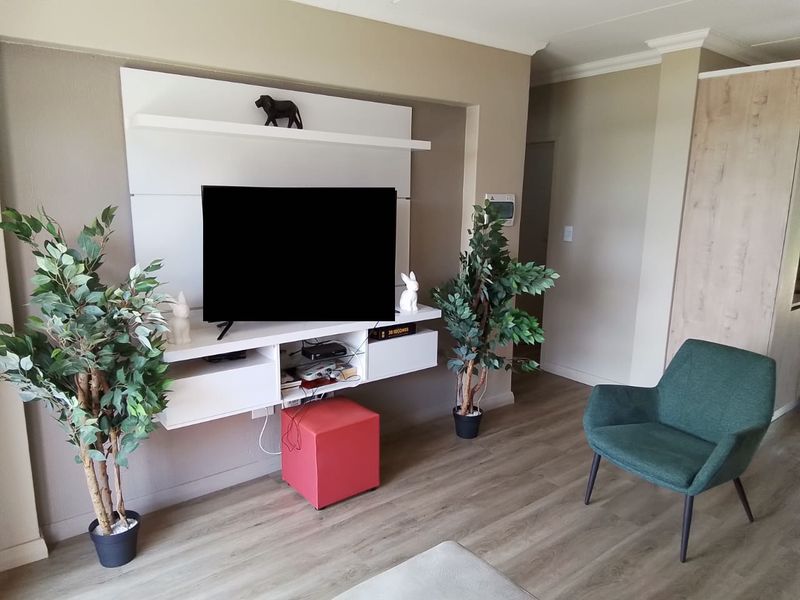 A living room featuring a modern wall-mounted media console and light-toned laminate flooring with decorative coving.