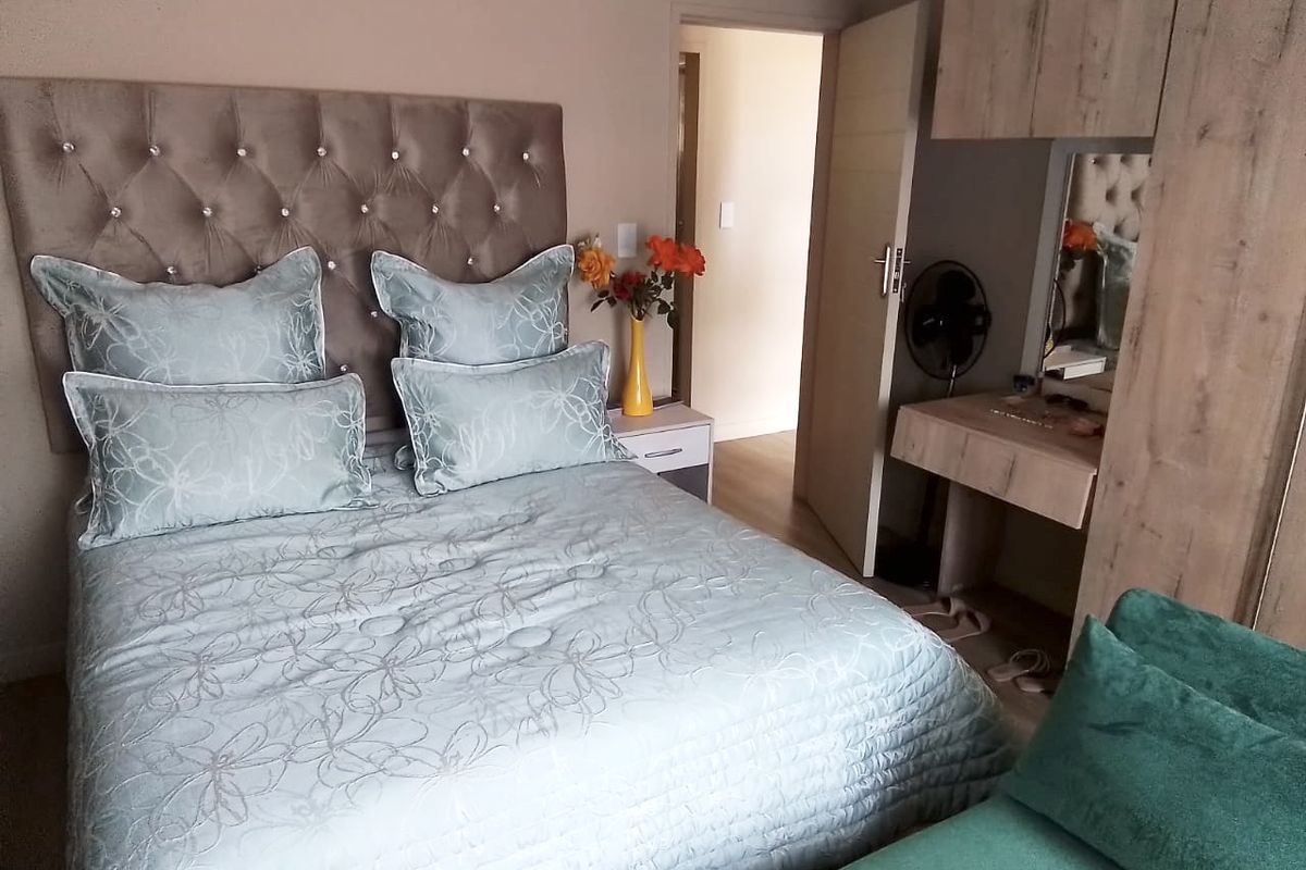 A well-maintained bedroom featuring built-in cabinetry, a vanity unit, and neutral finishes, providing a functional and comfortable living space.