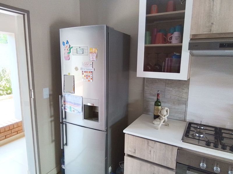A functional kitchen area featuring modern wood-finish cabinetry, stone countertops, a gas hob, and an integrated extractor fan.