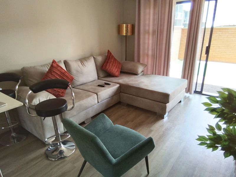 A comfortable living room featuring laminate flooring and a large sliding glass door providing access to the outdoor area.