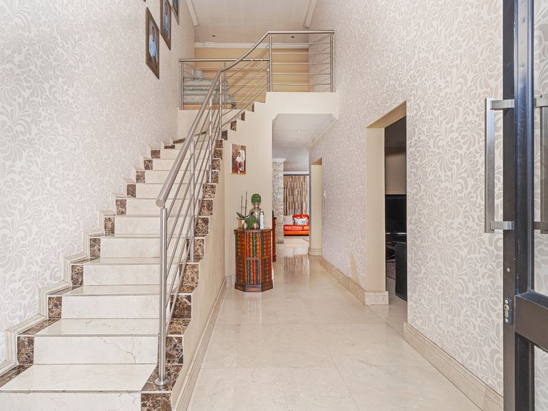 Spacious entrance hall featuring a grand marble staircase with stainless steel balustrades and elegant patterned wallpaper throughout.