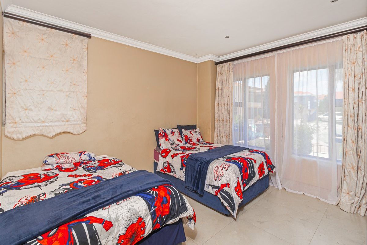 Spacious bedroom featuring tiled flooring, recessed lighting, and large sliding glass doors providing natural light and access to the exterior.