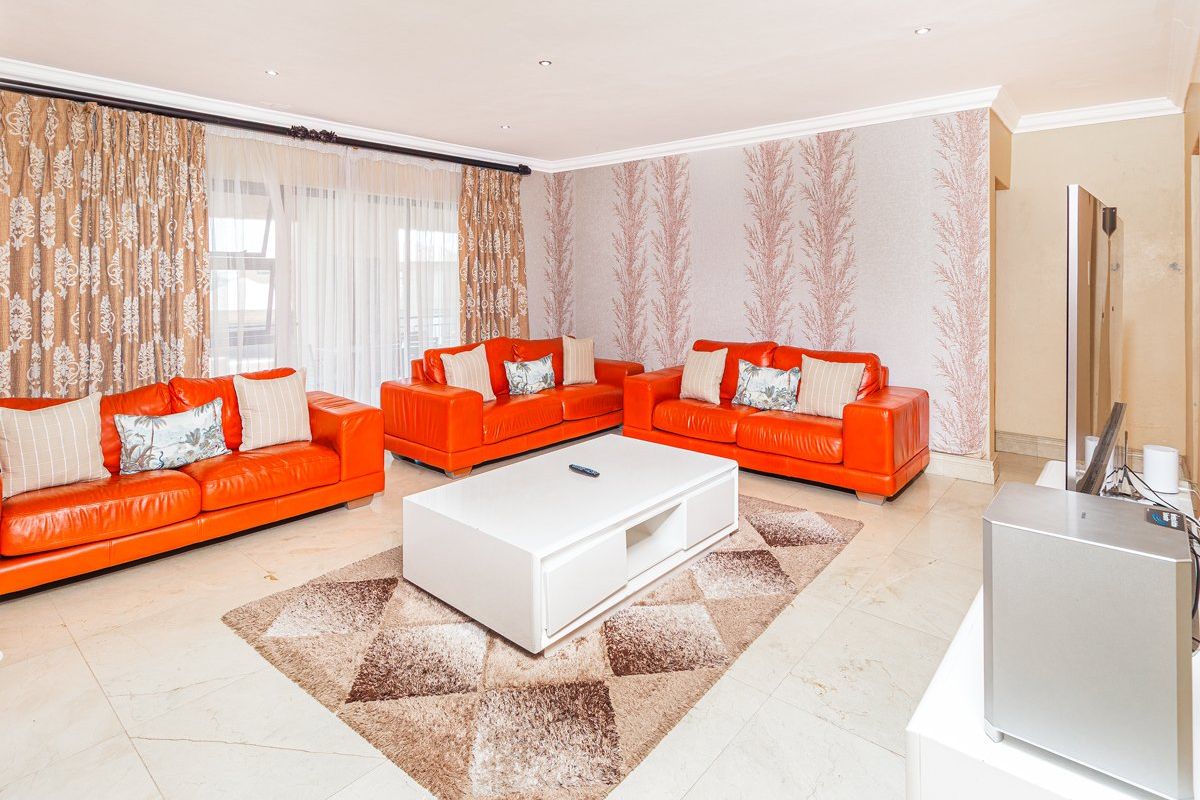 Spacious living room featuring tiled flooring, recessed downlighting, and large sliding glass doors providing access to the exterior.