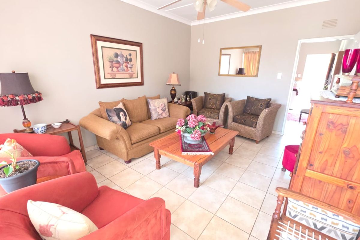 A comfortable living room featuring tiled flooring, a ceiling fan, and neutral wall finishes, providing a functional and well-lit space for relaxation.