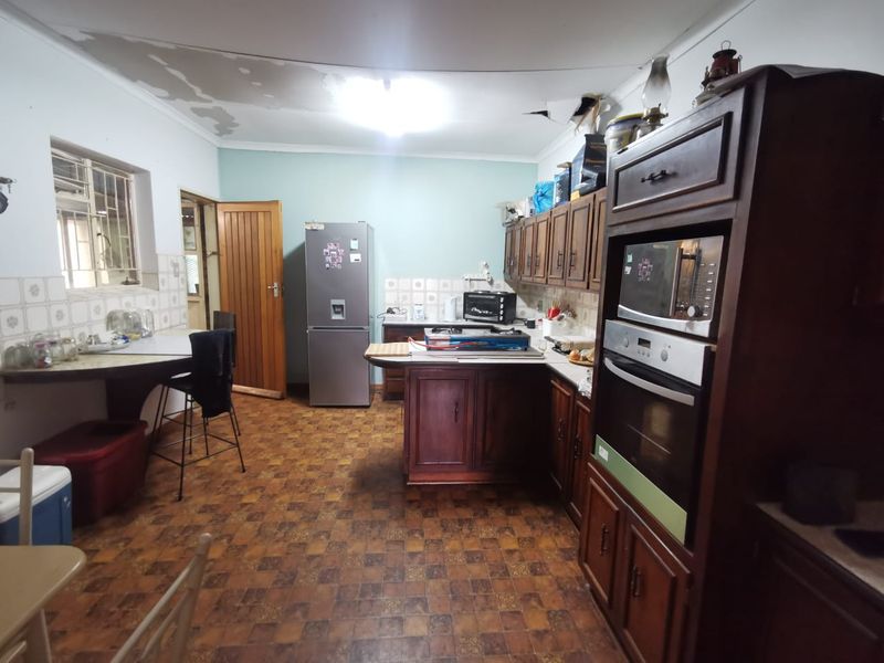 A dated kitchen featuring dark wood cabinetry, built-in oven, and tiled backsplash, requiring cosmetic updates to the ceiling and flooring.