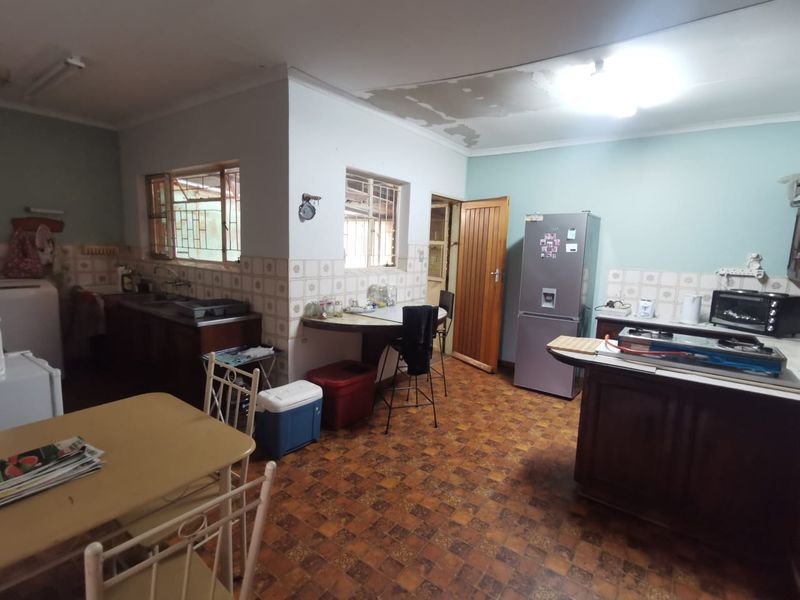 A dated kitchen featuring wooden cabinetry, tiled splashbacks, and a breakfast nook, requiring cosmetic updates and ceiling repairs.