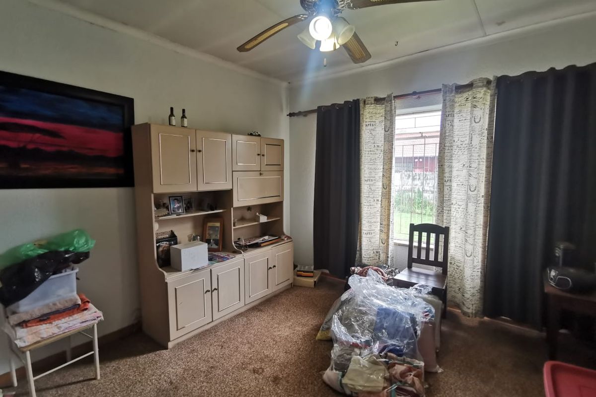 A bedroom featuring a ceiling fan, carpeted flooring, and a window with curtain treatments.