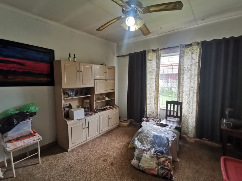 A bedroom featuring a ceiling fan, carpeted flooring, and a window with curtain treatments.