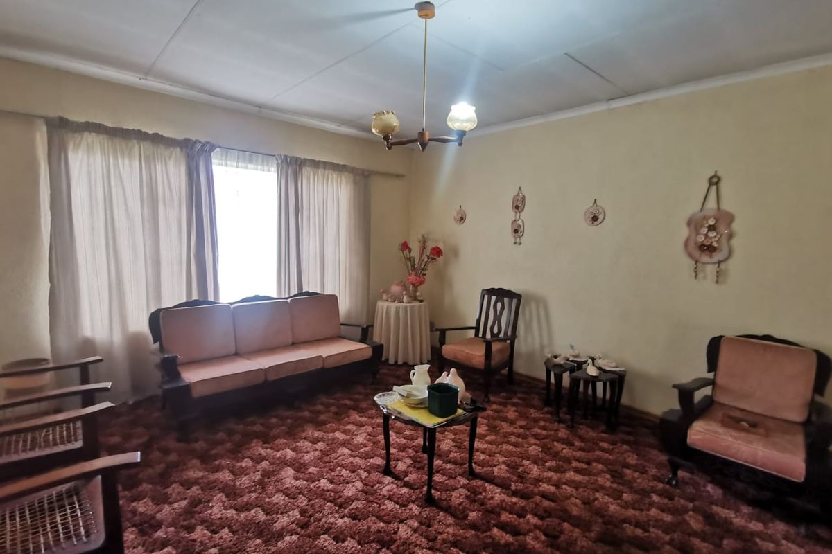 A dated living room featuring textured wall finishes, a traditional chandelier, and wall-to-wall carpeting, offering a blank canvas for modern renovation.