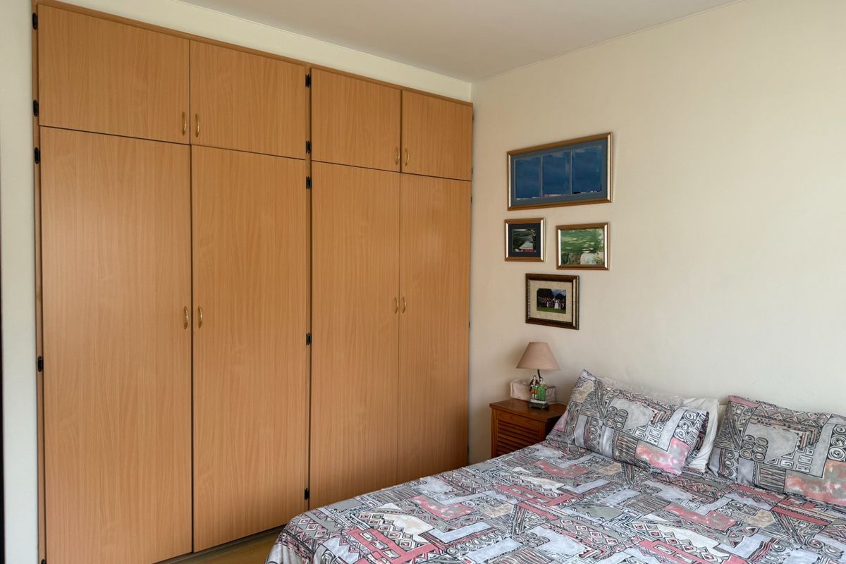 A bedroom featuring light wood-finish built-in cupboards and laminate flooring, offering practical storage space.