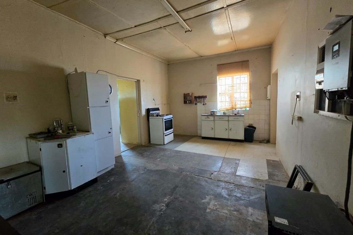 A dated kitchen area featuring basic cabinetry, a freestanding stove, and an installed inverter system, requiring significant renovation and cosmetic updates.