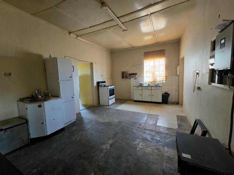 A dated kitchen area featuring basic cabinetry, a freestanding stove, and an installed inverter system, requiring significant renovation and cosmetic updates.