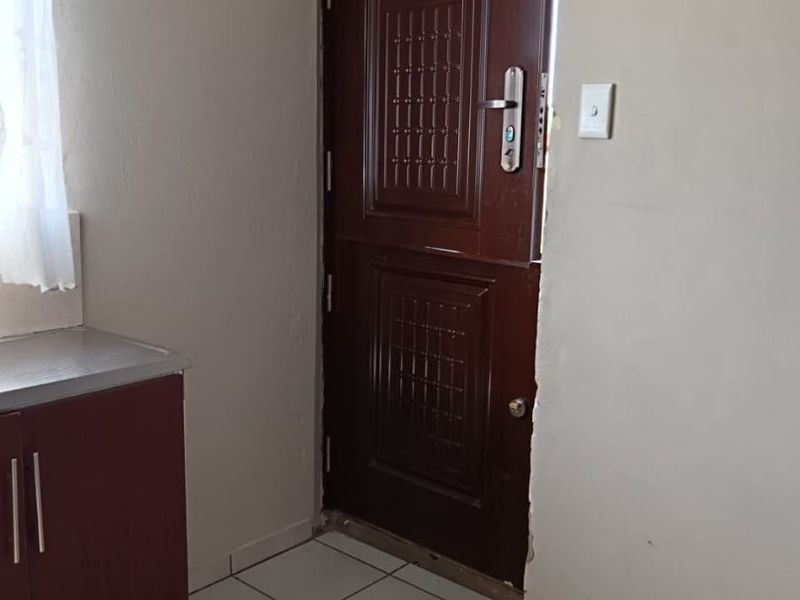 An entry area featuring tiled flooring, a dark wood stable door, and built-in cabinetry, showing signs of wear around the door frame.