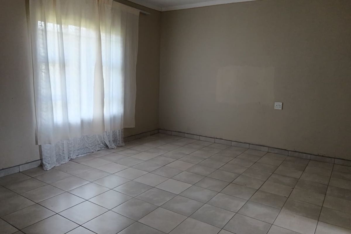 An empty living room featuring neutral wall tones and ceramic tiled flooring, providing a blank canvas for interior design and personalization.