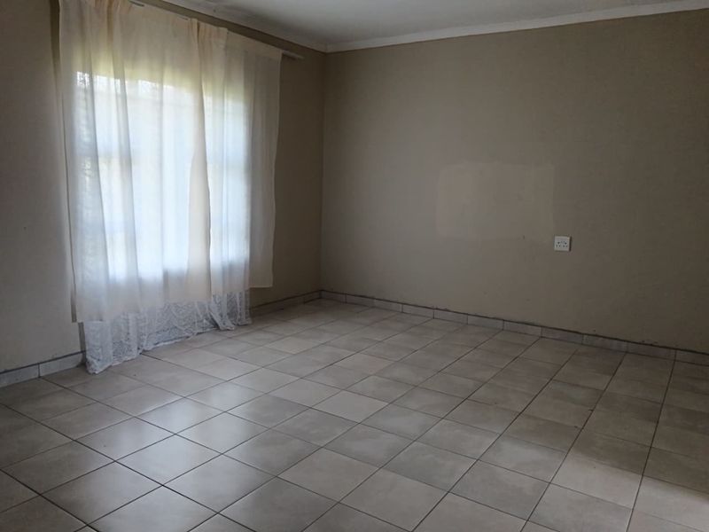 An empty living room featuring neutral wall tones and ceramic tiled flooring, providing a blank canvas for interior design and personalization.