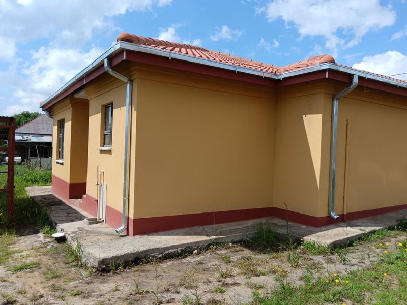 Rear exterior view of the house featuring a terracotta tiled roof, galvanized gutters, and a concrete apron surrounding the building perimeter.